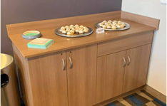 Counter with cabinets underneath that has plates of snacks on it